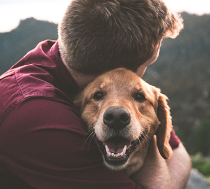 Boy hugging smiling golden retriever outdoors
